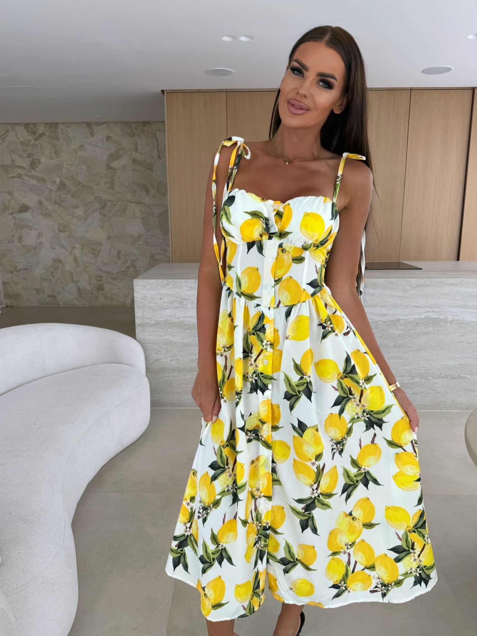 Woman wearing a dress with lemon print in a modern indoor setting