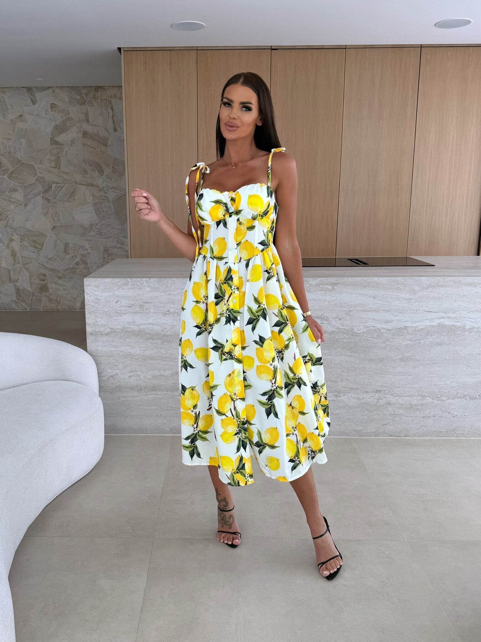Woman wearing a yellow and white floral dress in an indoor setting