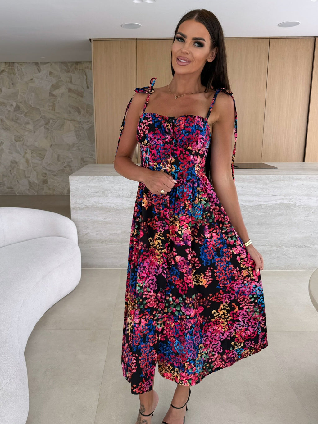 Woman wearing a colorful floral dress in an indoor setting
