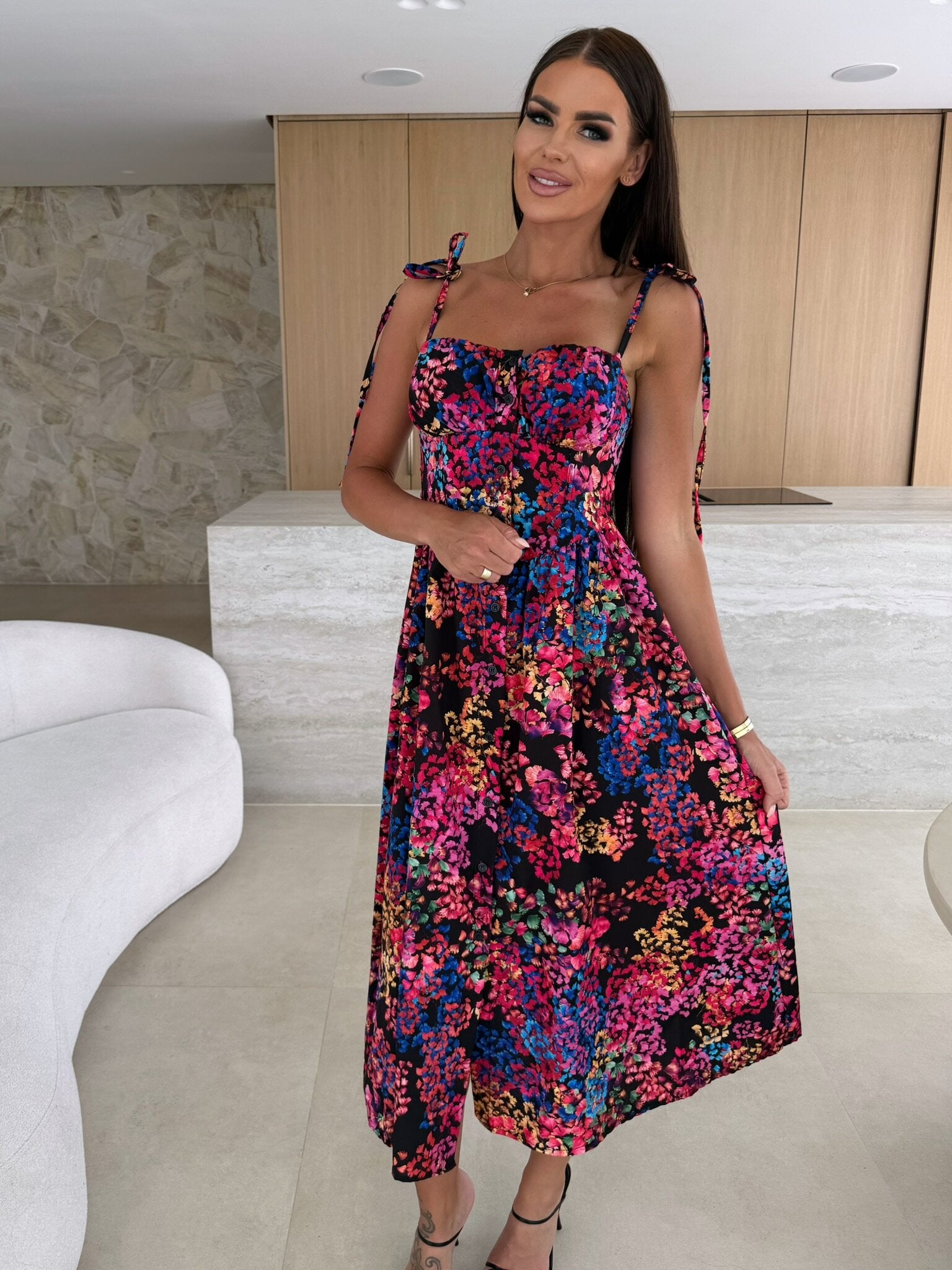 Woman wearing a colorful floral dress in an indoor setting