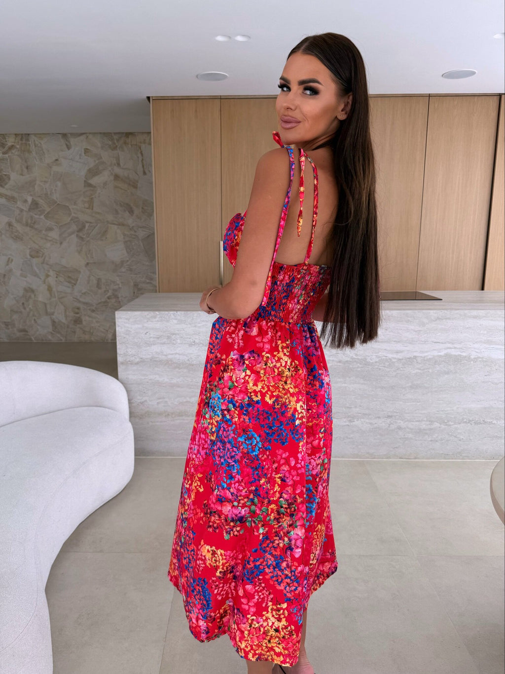 Woman in a colorful dress standing in an indoor setting with a neutral background