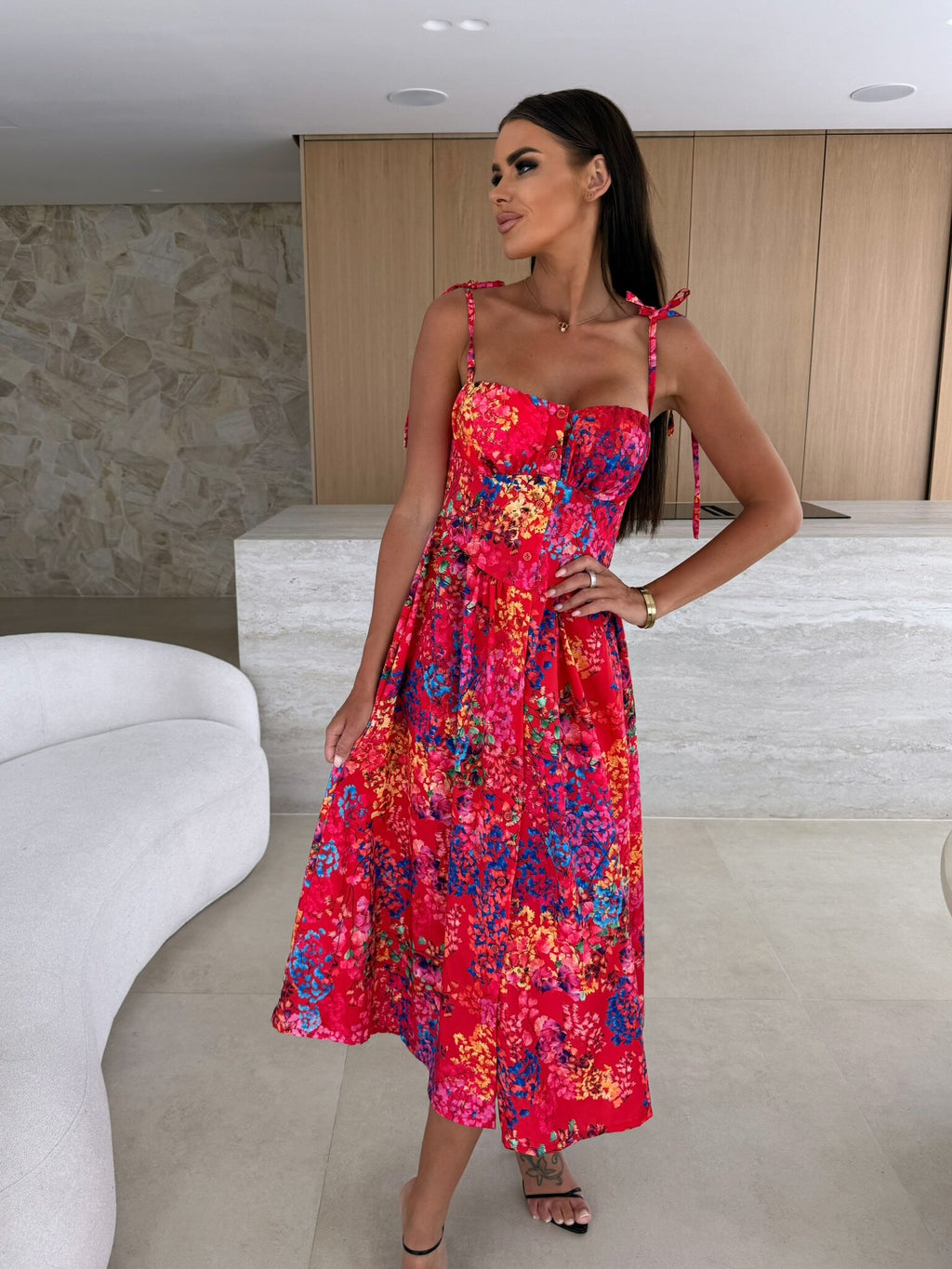 Woman wearing a colorful floral dress in an indoor setting