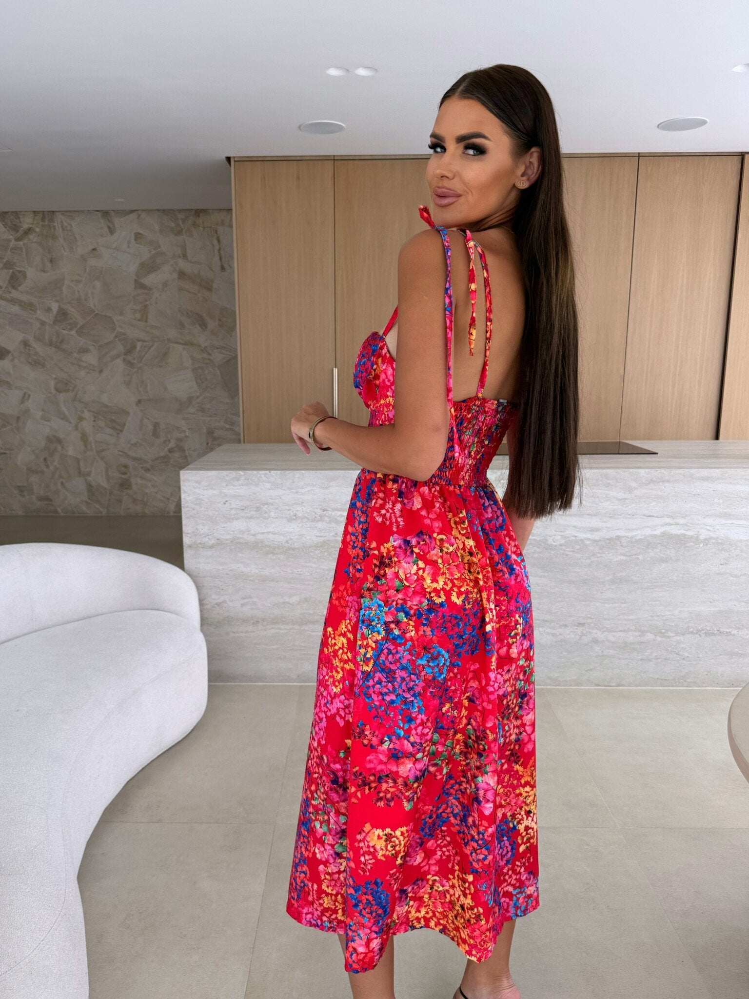 Woman in a colorful floral dress standing in a modern indoor setting.