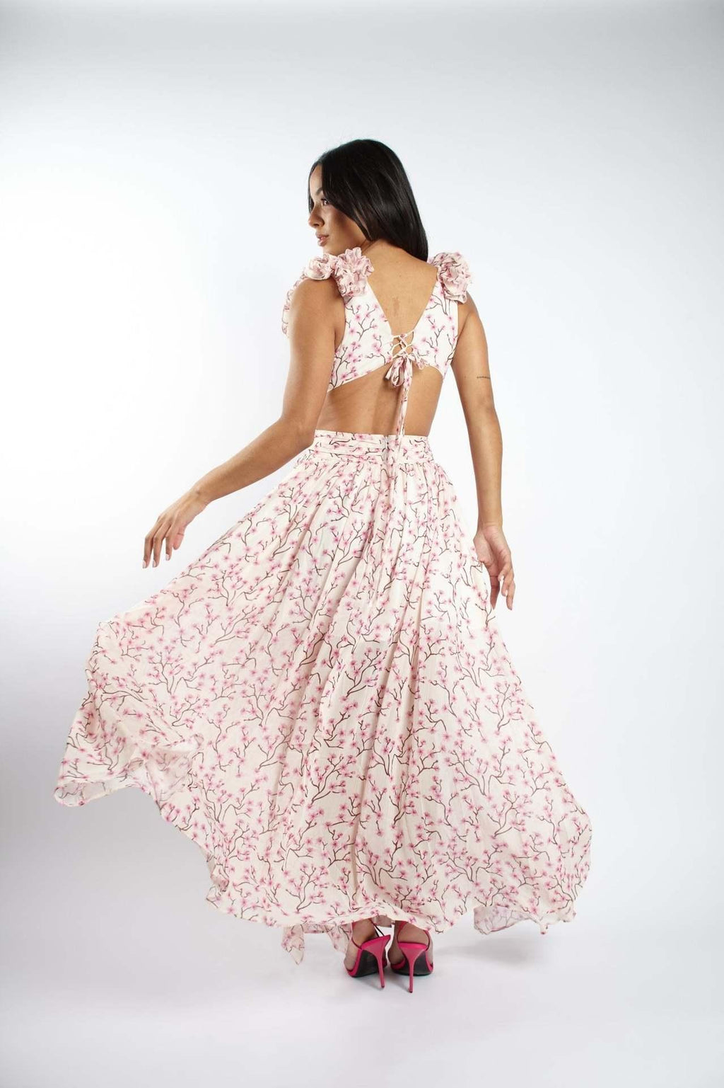 Woman wearing a pink floral dress with a cut-out back on a white background