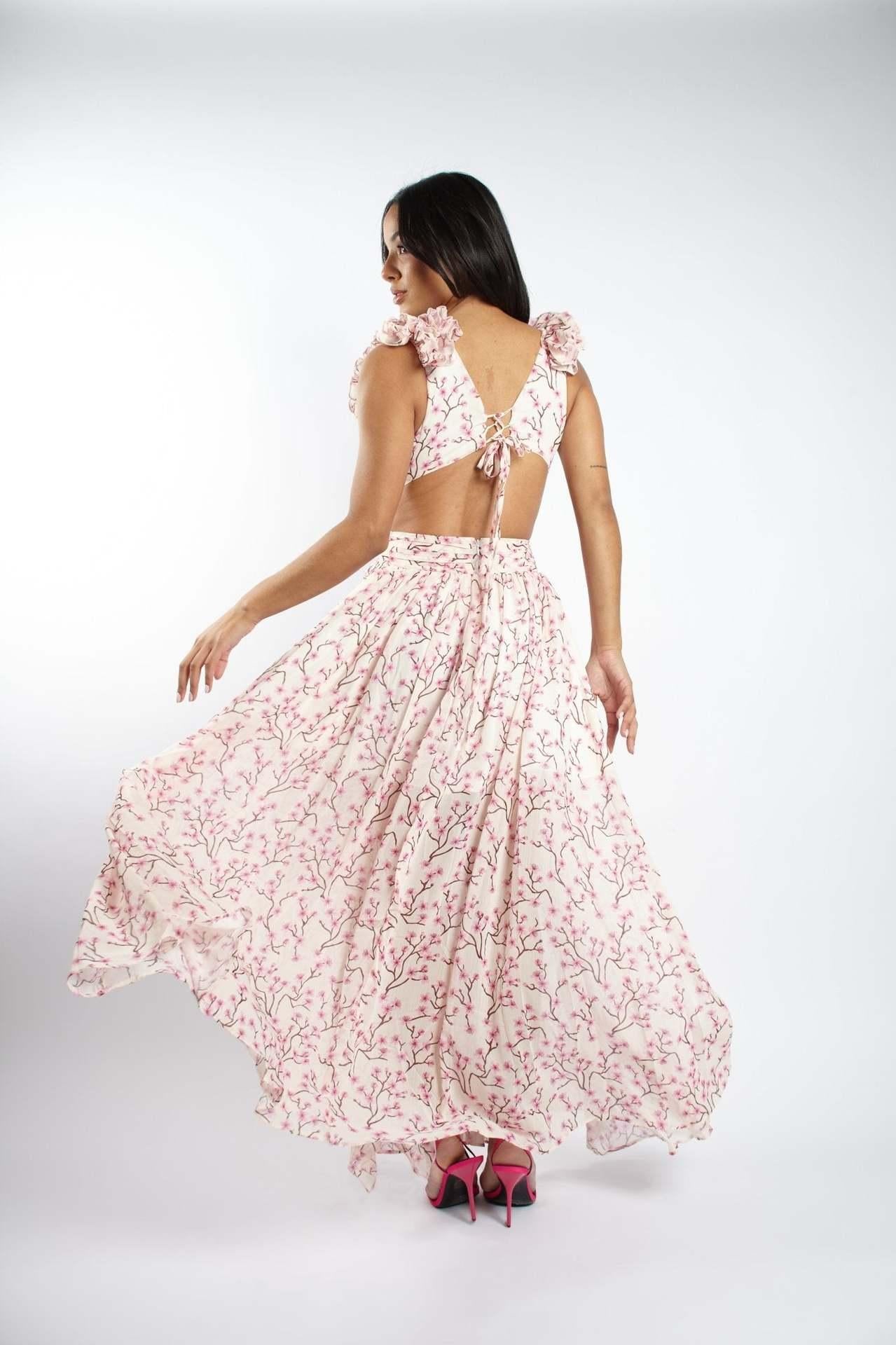 Woman wearing a pink floral dress with a cut-out back on a white background