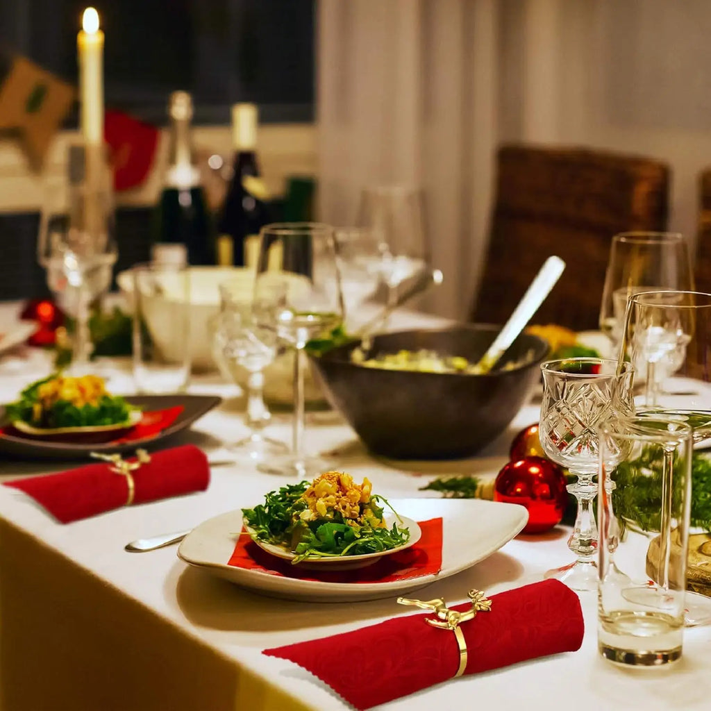 Dining table set for a meal with plates, glasses, and candles in a cozy indoor setting.