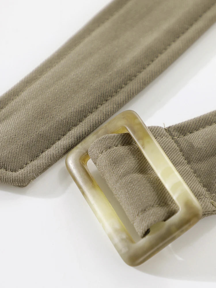 Close-up of a beige belt with a square buckle on a white background