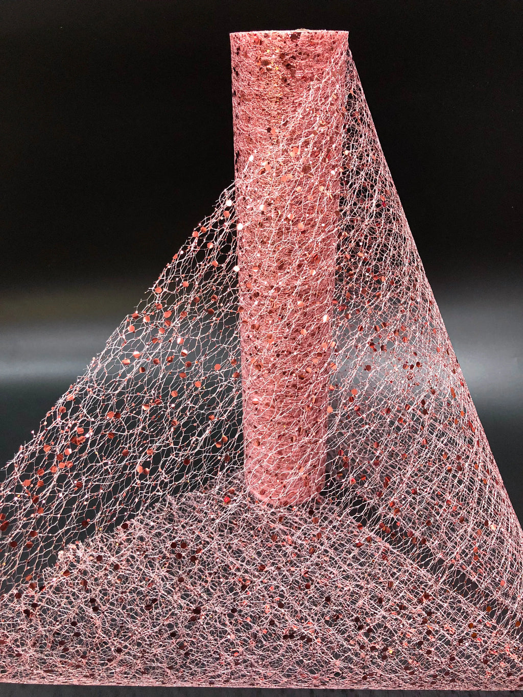 Close-up of a textured pink material with a cone-shaped object on a black background