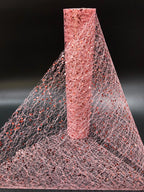 Close-up of a textured pink material with a cone-shaped object on a black background