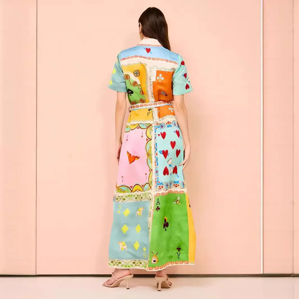 Woman wearing a colorful patchwork dress against a pink wall.