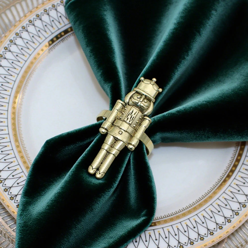 Gold nutcracker napkin ring on a green napkin over a decorative plate.