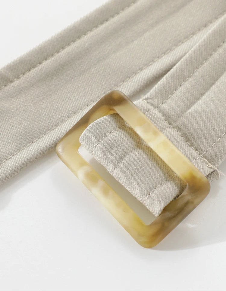 Close-up of a beige belt with a rectangular buckle on a light background