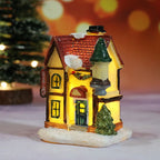 Decorative miniature house with a lit interior, surrounded by festive decorations on a blurred background.