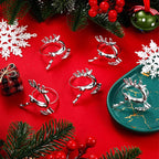 Silver reindeer-shaped drink holders on a red surface with Christmas decorations.