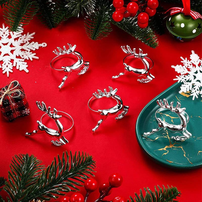 Silver reindeer-shaped drink holders on a red surface with Christmas decorations.