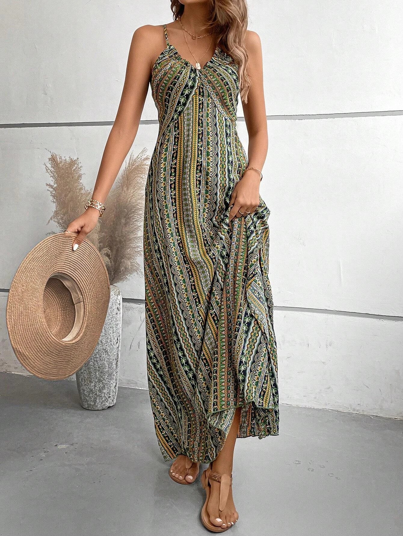 Woman wearing a patterned dress holding a straw hat against a white wall.