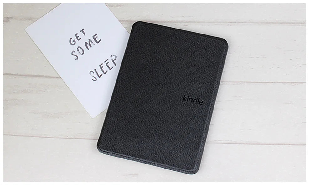 Black Kindle cover on a light wooden surface with a white card reading 'Get some sleep'.