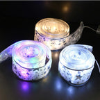 Three rolls of LED strip lights glowing in different colors on a dark surface.