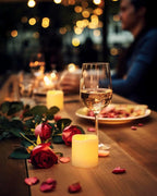 Romantic dinner setting with wine glass, candles, and flowers on a wooden table.