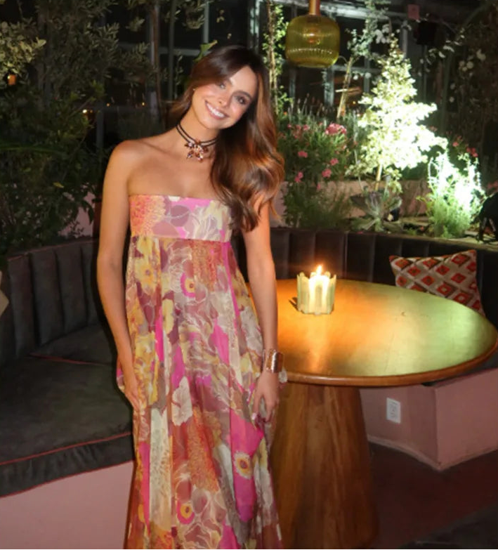 Woman in a colorful dress standing in an outdoor setting with a candle on a table.
