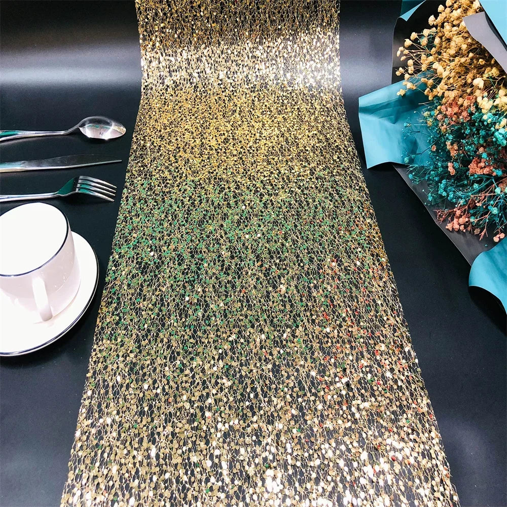Gold sequin table runner on a black table with silverware and a cup.