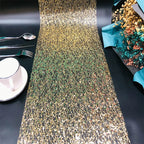 Gold sequin table runner on a black table with silverware and a cup.