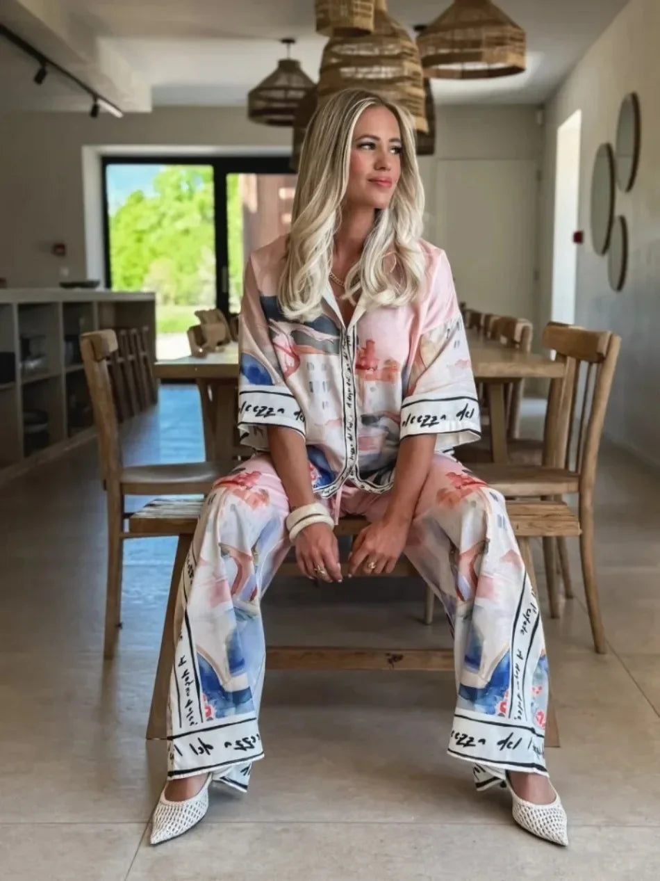 Woman sitting on a chair in a modern dining area wearing a colorful outfit.