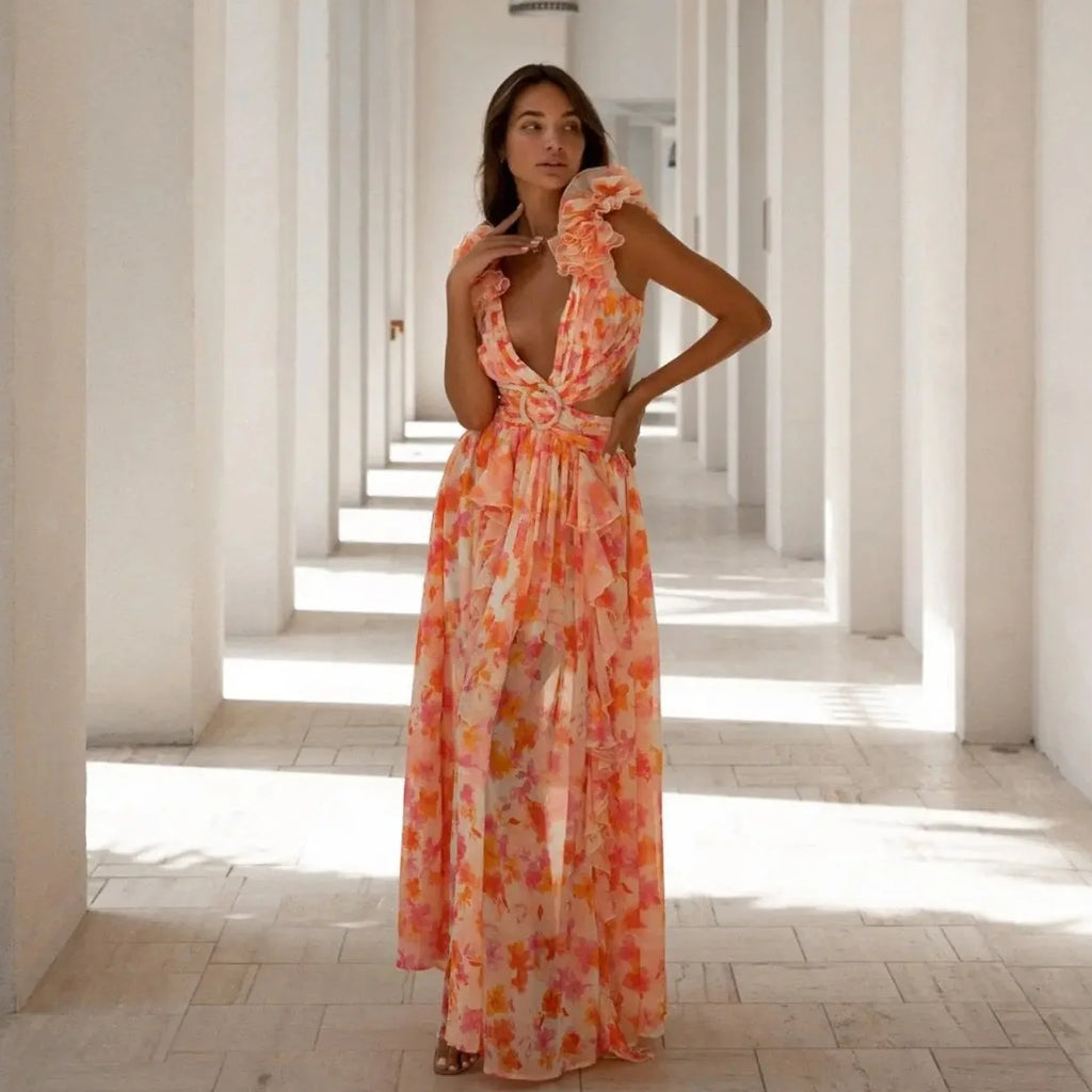 Woman in a floral dress standing in a sunlit hallway with columns.
