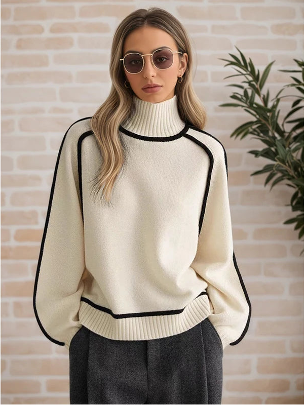 Woman wearing a cream sweater with black accents against a brick wall.