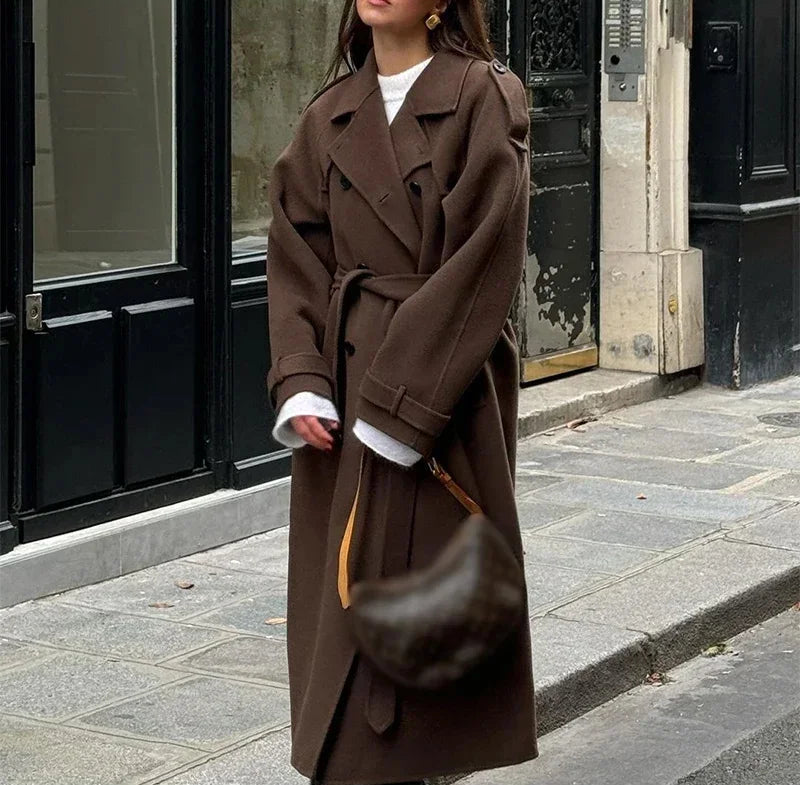 Person wearing a long brown coat on a city street.
