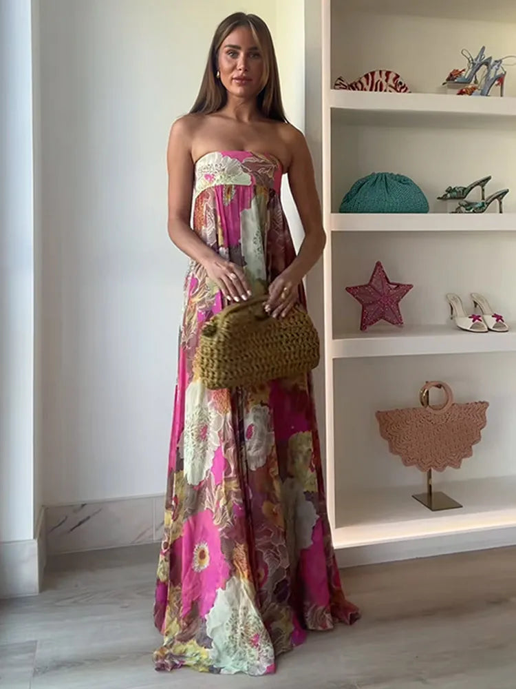Woman in a floral strapless dress holding a handbag in a room with shelves displaying bags and shoes.