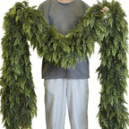 Person holding a large green artificial garland against a white background