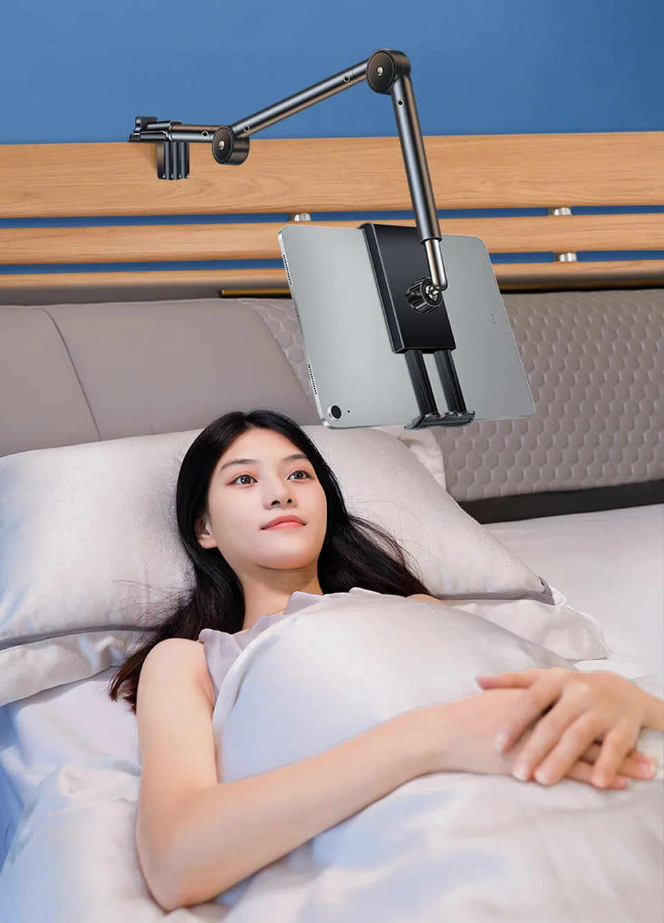 Woman lying in bed with a tablet holder above her headboard