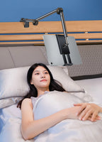 Woman lying in bed with a tablet holder above her headboard