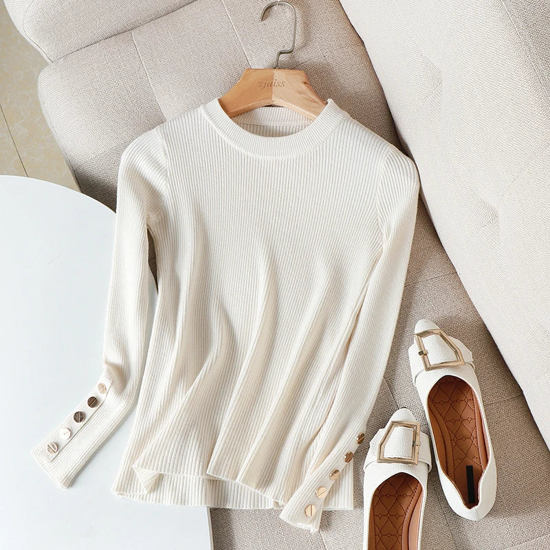 White ribbed sweater on a hanger with white flats on a light wooden floor.