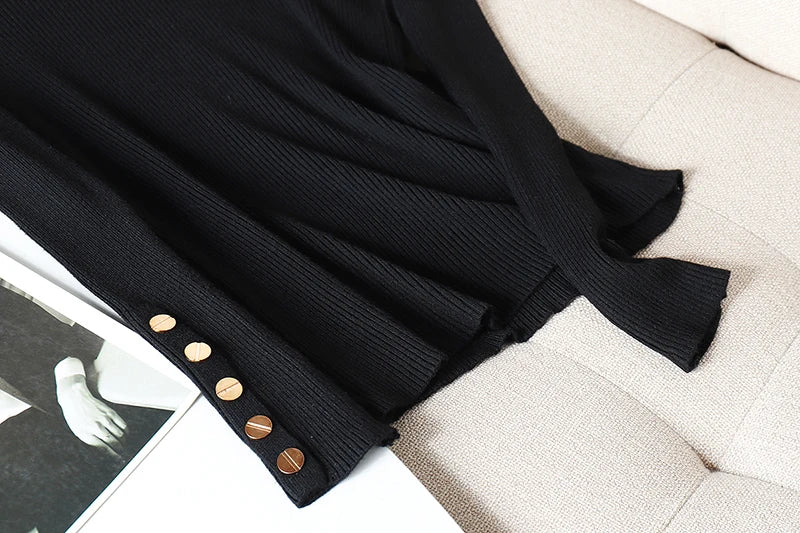 Black ribbed sweater with gold buttons on a beige surface