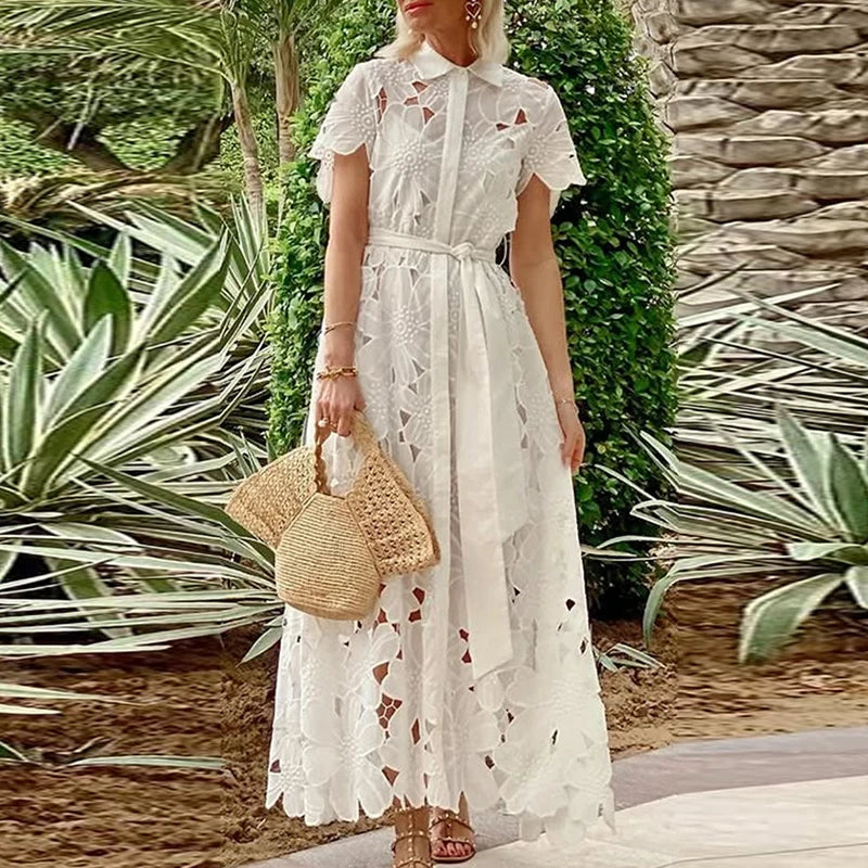 Woman in a white lace dress holding a straw bag in a garden setting