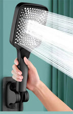Handheld shower head with water spraying out, held by a hand against a teal background