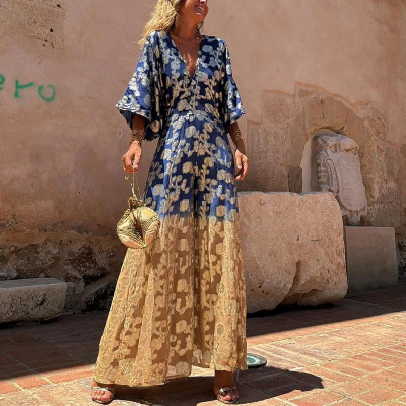 Woman wearing a blue and beige floral dress standing in front of stone ruins.