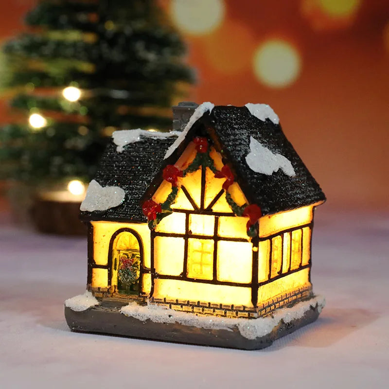 Decorative lit house with snow on the roof, Christmas tree in the background