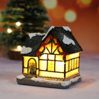 Decorative lit house with snow on the roof, Christmas tree in the background