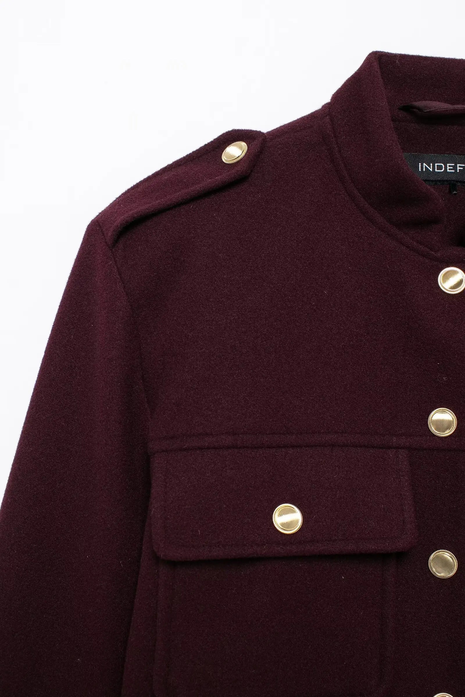 Close-up of a dark purple coat with gold buttons on a white background