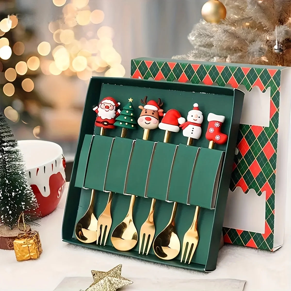Set of gold Christmas-themed spoons in a decorative box with a festive background.
