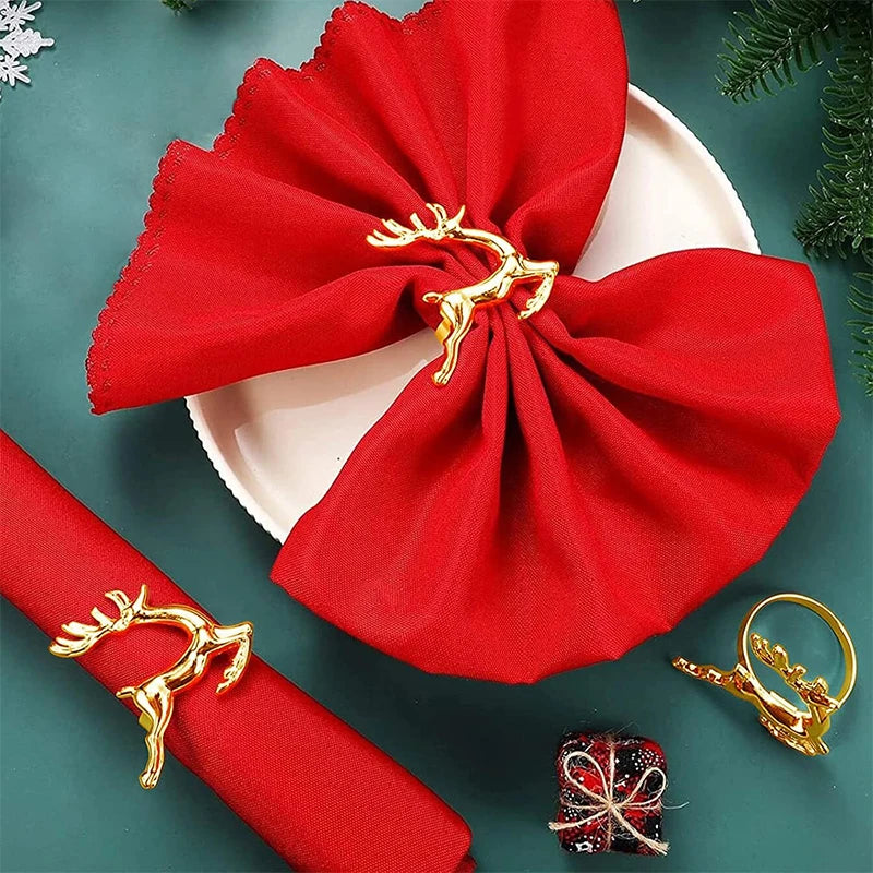 Red napkin with gold reindeer holder on a green surface with Christmas decorations.