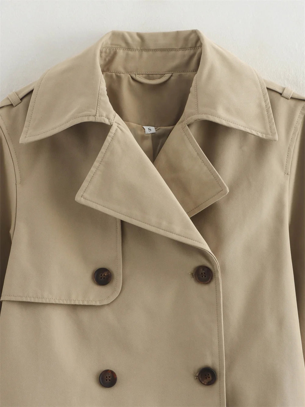 Beige trench coat with double-breasted buttons on a light gray background