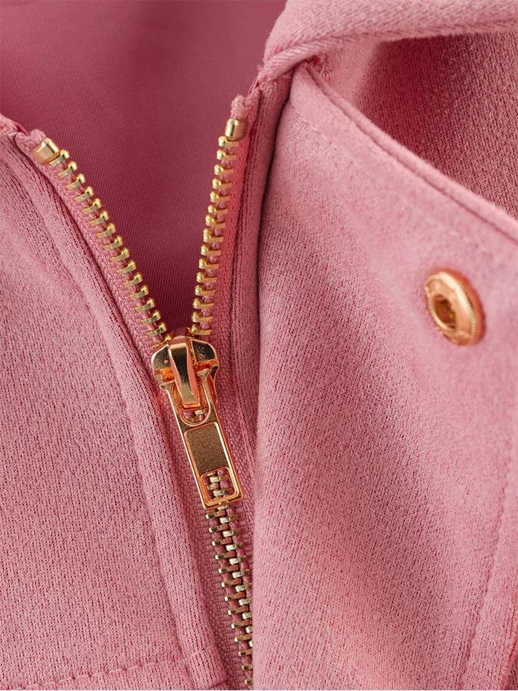 Close-up of a pink jacket with a gold zipper and button.