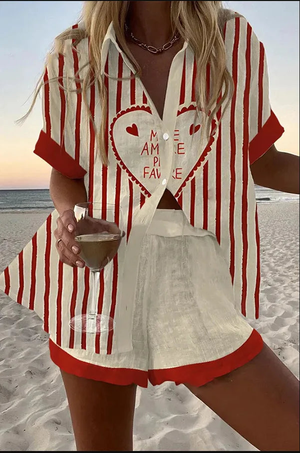 Person wearing a red and white striped shirt with a heart design on a beach.