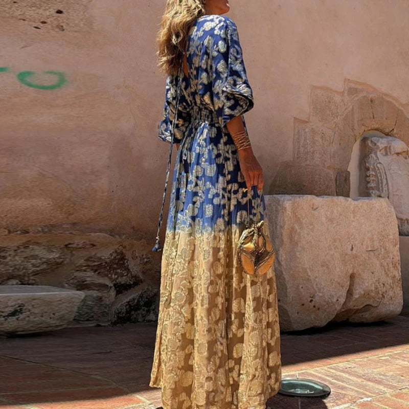 Woman in a blue and gold dress standing in front of stone architecture.