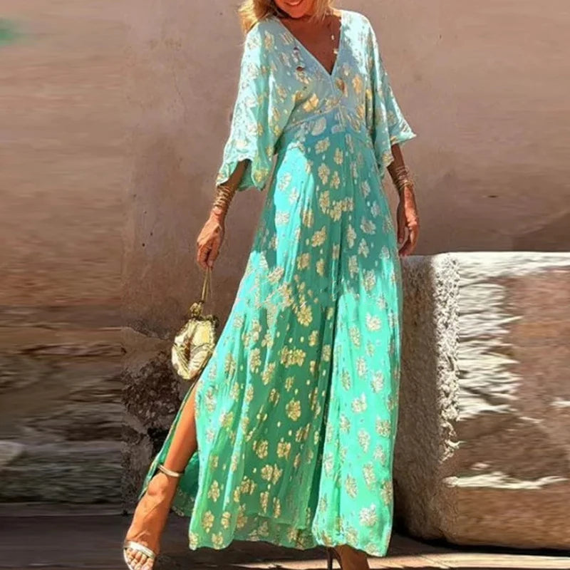 Woman wearing a teal floral dress standing against a textured wall.