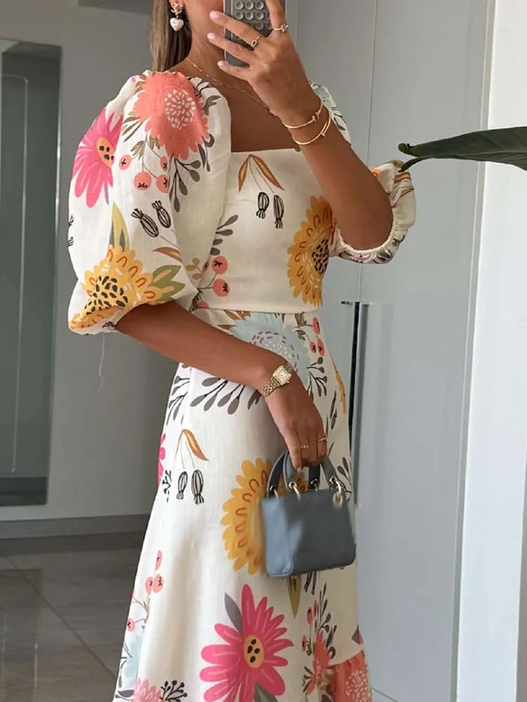 Person wearing a floral dress with colorful flowers, taking a mirror selfie.